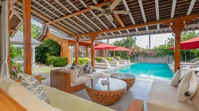 an outdoor living room with a pool and tables and chairs at Villa Taramille by Villa Finder in Kerobokan