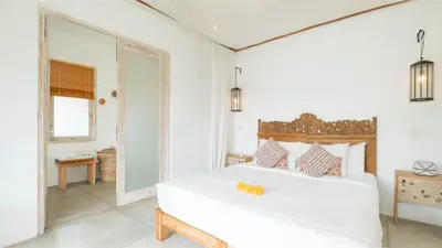 a white bedroom with a large white bed and a window at Villa Alea by Villa Finder in Kerobokan