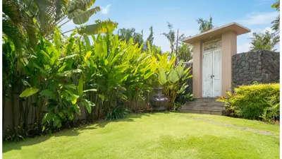 a garden with a white door and some plants at Villa Alea by Villa Finder in Kerobokan