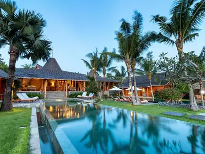 a villa with a swimming pool in front of a house at Villa Mannao by Villa Finder in Kerobokan