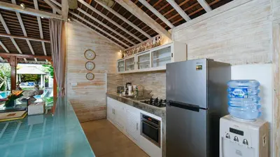 a kitchen with a refrigerator and a counter top at Villa Little Mannao by Villa Finder in Kerobokan