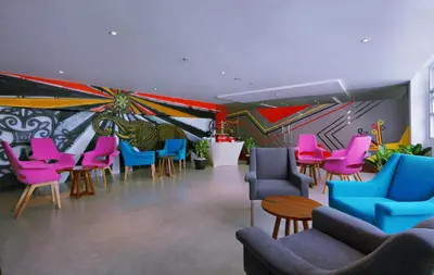 a waiting room with colorful chairs and a mural at favehotel Kuta Kartika Plaza in Kuta