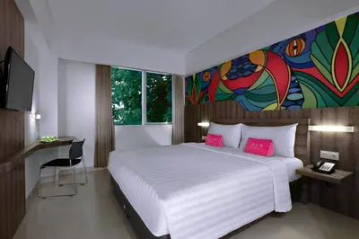 a bedroom with a large white bed with pink pillows at favehotel Kuta Kartika Plaza in Kuta