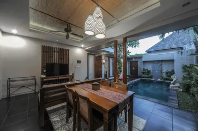 a dining room with a table and a swimming pool at Gaing Mas Jimbaran Villas by Gaing Mas Group in Jimbaran