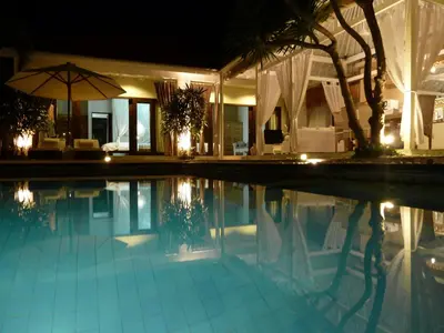 a swimming pool in front of a house at night at La Dolce Villa in Seminyak