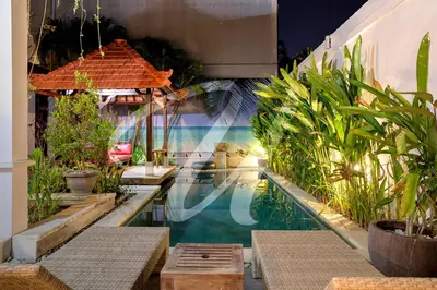 a swimming pool next to a building with plants at Vila Ultima Bali in Seminyak