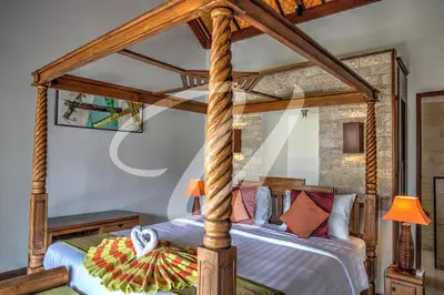a bedroom with a wooden canopy bed with pillows at Vila Ultima Bali in Seminyak
