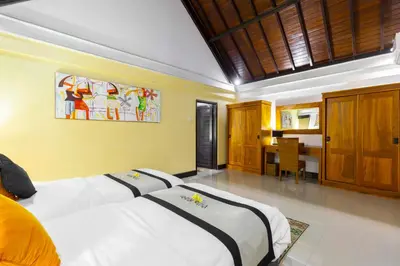a bedroom with two beds and a table in it at Villa Kibbi in Seminyak