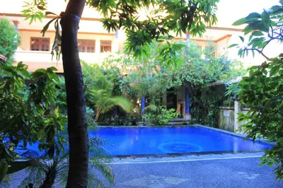 a swimming pool in the middle of a yard with trees at Losmen Cempaka 3 in Kuta