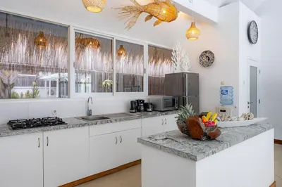 a kitchen with white cabinets and a bowl of fruit on a counter at Villa Blue Pearl by Optimum Bali Villas in Seminyak