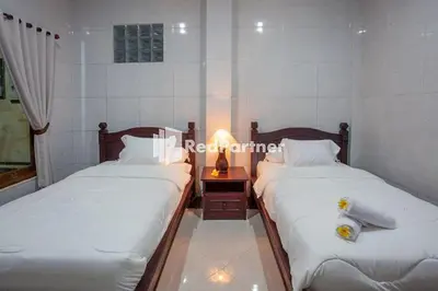 two twin beds in a room with a lamp at Wita Homestay Berawa in Canggu