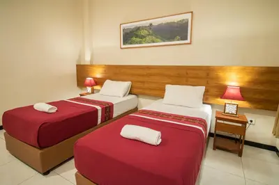 a hotel room with two beds and a table at Kuta Suci Guesthouse in Kuta