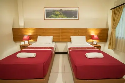 two beds in a room with two red beds at Kuta Suci Guesthouse in Kuta