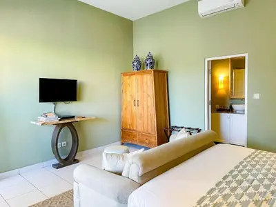 a bedroom with a bed and a couch and a television at Room Sweet Room - Seminyak Center, walk to the Beach in Seminyak