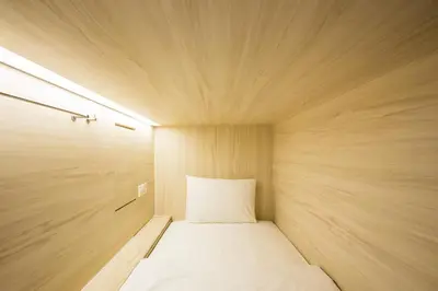 a small room with a white bed in it at H-ostel Bali in Kuta