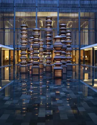 a building with a pool of water with tables and chairs at The Anvaya Beach Resort Bali in Kuta