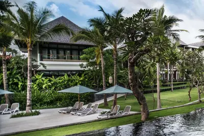 a resort with chairs and umbrellas next to a pool at The Anvaya Beach Resort Bali in Kuta