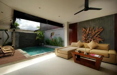 a living room with a couch and a swimming pool at Sudha Villa Bali Baik-Baik in Seminyak