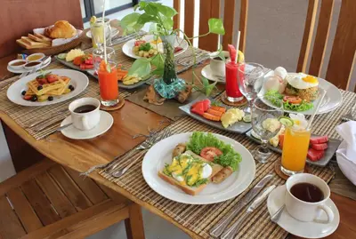 a table with plates of food and cups of coffee at Sudha Villa Bali Anyelir in Seminyak