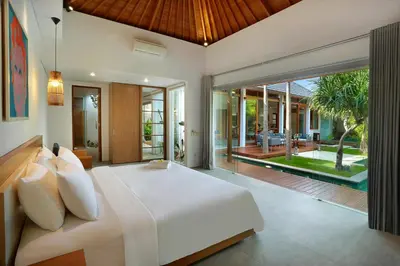 a bedroom with a large bed and a swimming pool at Villa Odyssey in Seminyak
