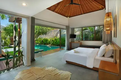 a bedroom with a large bed and a pool at Villa Odyssey in Seminyak