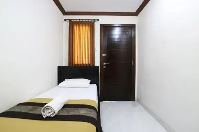 a small bedroom with a bed and a brown door at Pondok 3 Mertha in Kuta