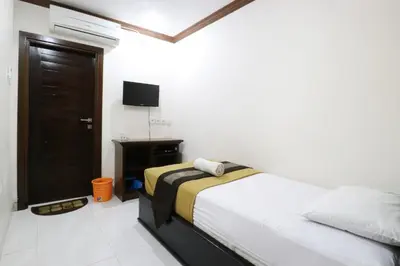 a bedroom with a bed and a desk and a television at Pondok 3 Mertha in Kuta