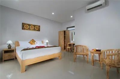 a bedroom with a bed and a table and chairs at Sleepwell Seminyak in Seminyak