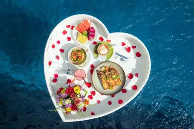 a plate of food on a heart shaped table next to the water at Sleepwell Seminyak in Seminyak
