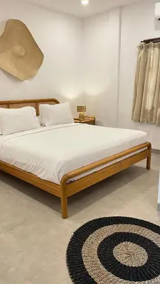a bed with white sheets and a rug in a room at Baliana Villa Legian in Legian