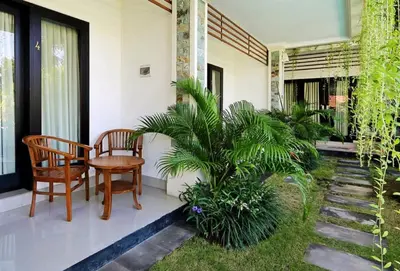 a porch of a house with two chairs and a table at Indah Homestay in Seminyak