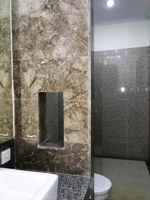 a bathroom with a stone shower with a toilet and a sink at Indah Homestay in Seminyak