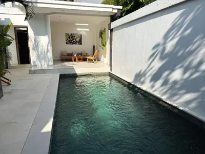 a swimming pool in front of a house at Aster Villa Seminyak in Seminyak