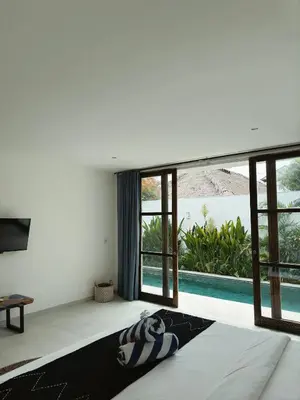 a bedroom with a bed with a view of a pool at Aster Villa Seminyak in Seminyak