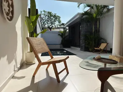 a wooden chair sitting on a patio with a table at Aster Villa Seminyak in Seminyak