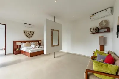 a bedroom with a bed and a couch and a mirror at Villa Belle Seminyak by Exotic Bali Properties in Seminyak