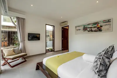 a bedroom with a large bed and a chair at Villa Belle Seminyak by Exotic Bali Properties in Seminyak