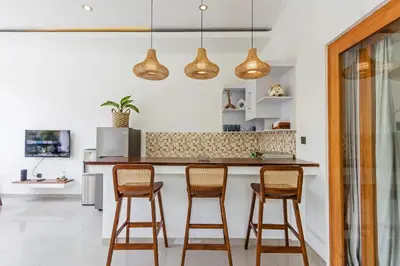 a kitchen with three bar stools and three lights at Adorable 1BR villas in the heart of Seminyak in Seminyak
