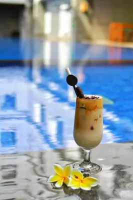 a drink sitting on a table next to a pool at Swiss-Belexpress Kuta Legian in Kuta