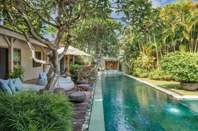 a pool in the backyard of a house with trees at Villa Cinta Damai - Stunning & Stylish 4BR Luxury Villa in the Heart of Seminyak, Just a 10-Min Walk to the Beach in Seminyak