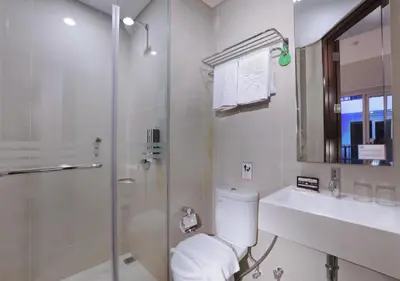 a bathroom with a shower and a toilet and a sink at Fame Hotel Sunset Road in Kuta