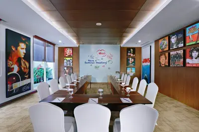 a conference room with a long table and white chairs at Fame Hotel Sunset Road in Kuta