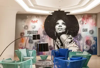 a room with chairs and a mural of a woman at Solia Legian Bali in Legian