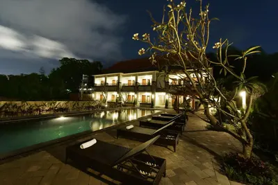 a resort with a swimming pool at night at Le Lima in Kuta