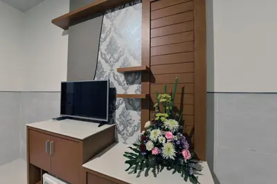 a room with a tv and flowers on a counter at Le Lima in Kuta