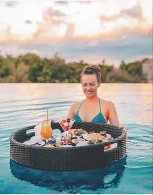 a woman in the water with a table of food in the water at FOX Hotel Jimbaran Beach Bali in Jimbaran