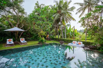 a swimming pool in front of a resort with palm trees at Villa Sally in Canggu
