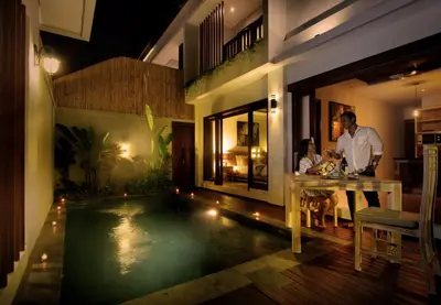 a man and a woman sitting at a table in front of a house at The Murdha Villa in Seminyak