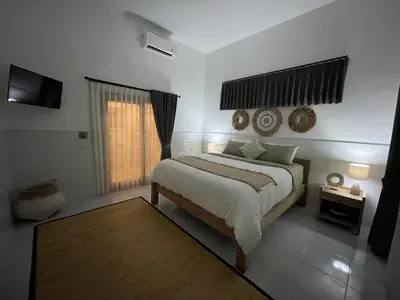 a bedroom with a large bed and a window at Pennylane Villa in Seminyak
