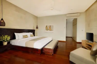 a bedroom with a large bed and a television at Villa Tenang by Nakula in Canggu